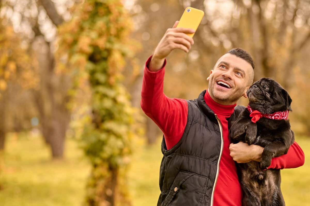 a man with his dog in hands making selfie 9HQXBMS